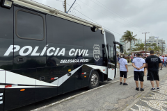 Policiais civis ao lado de viatura
