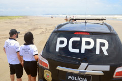 Dois policiais civis ao lado de viatura no litoral