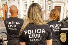 Três policiais civis de costas observando o movimento nas ruas