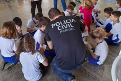 Policial civil de costas brincando com várias crianças