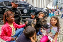 Policial civil observa crianças acariciando cão policial