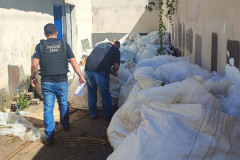 Dois policiais civis analisam sacos de fertilizante apreendidos