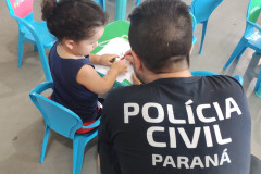 Policial civil ajudando criança a desenhar
