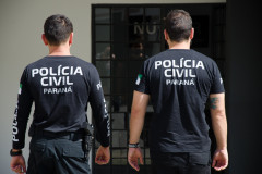 Dois policiais de costas entrando em delegacia