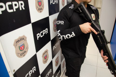 Policial civil empunha arma em frente a banner da PCPR