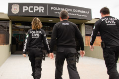 Três policiais civis entrando em delegacia