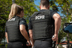 Dois policiais civis de costas empunhando armas